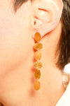 Gold earrings worn by a person with a blurred background
