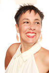 Woman wearing a white halter top with a plain background and earrings 