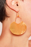 Gold hoop earring worn by a person with a neutral background