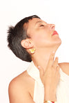 Woman with gold earring and necklace against a white background