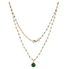 gold plated necklace with green gemstones on a white background