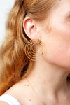 Close-up of spiral earrings showing hammered texture and brushed gold finish