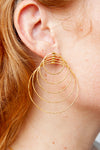 Versatile spiral earrings showing expanding circle pattern in hammered gold finish